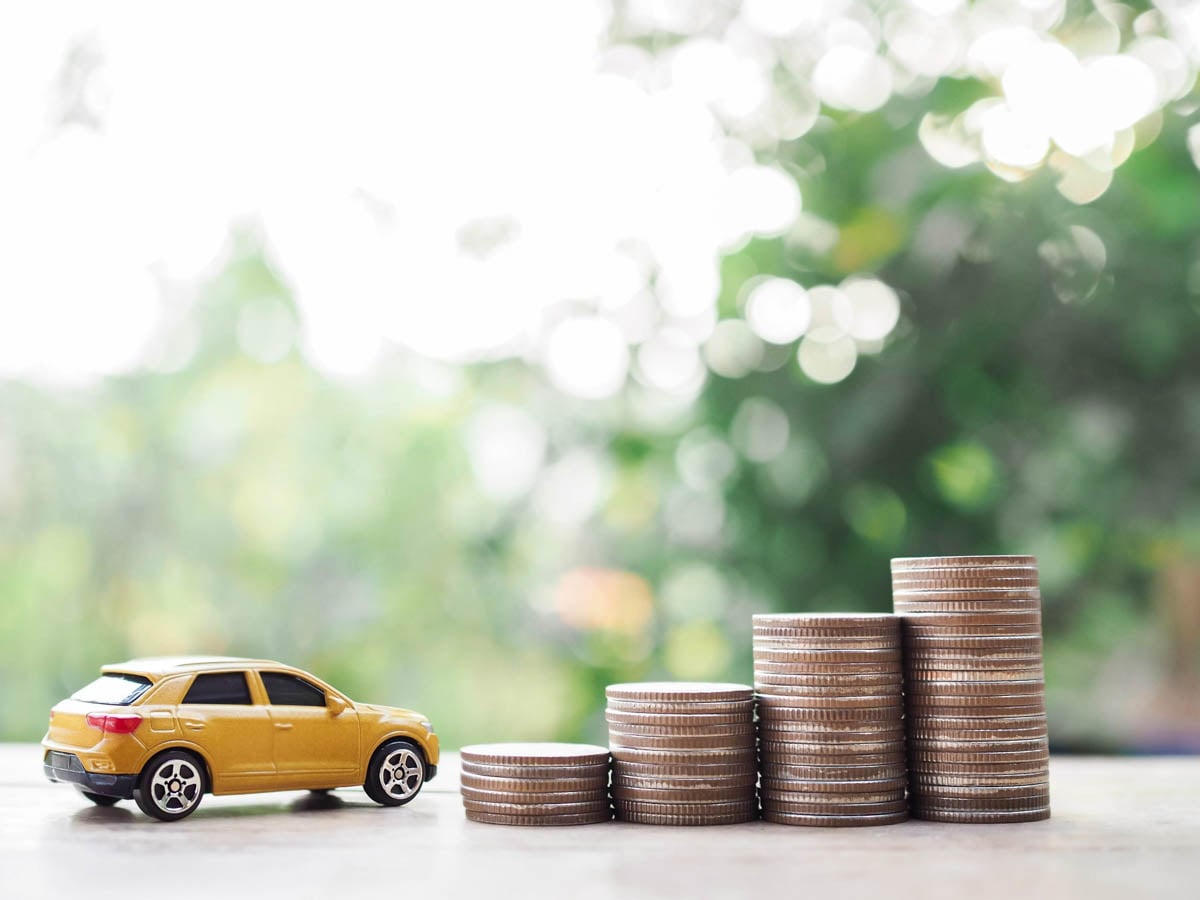 Miniatura de carro ao lado de uma pilha de moedas    