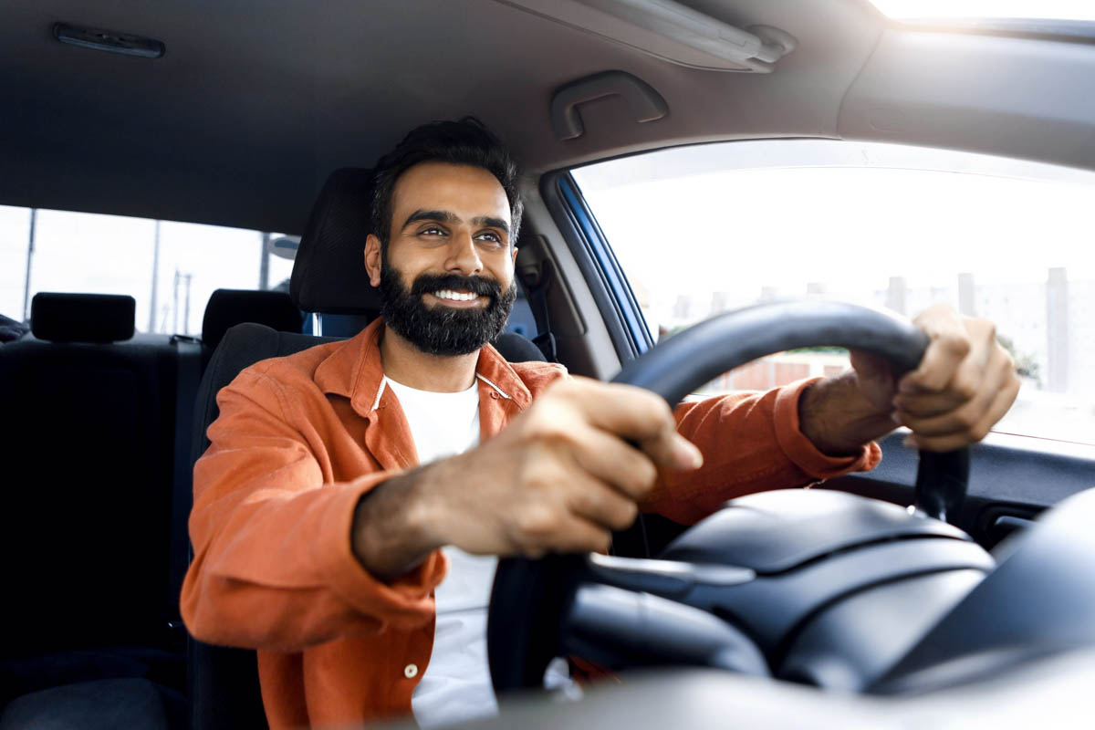 Homem dirigindo seu carro sorrindo         