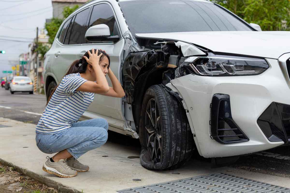 Mulher com as mãos na cabeça após colidir seu carro    
