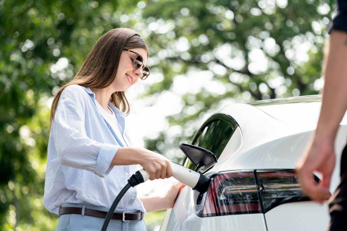 Mulher realizando o carregamento do veículo elétrico       
