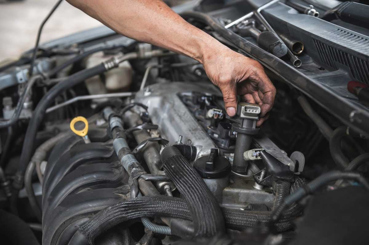 Mecânico fazendo a desmontagem da bobina de ignição do motor    