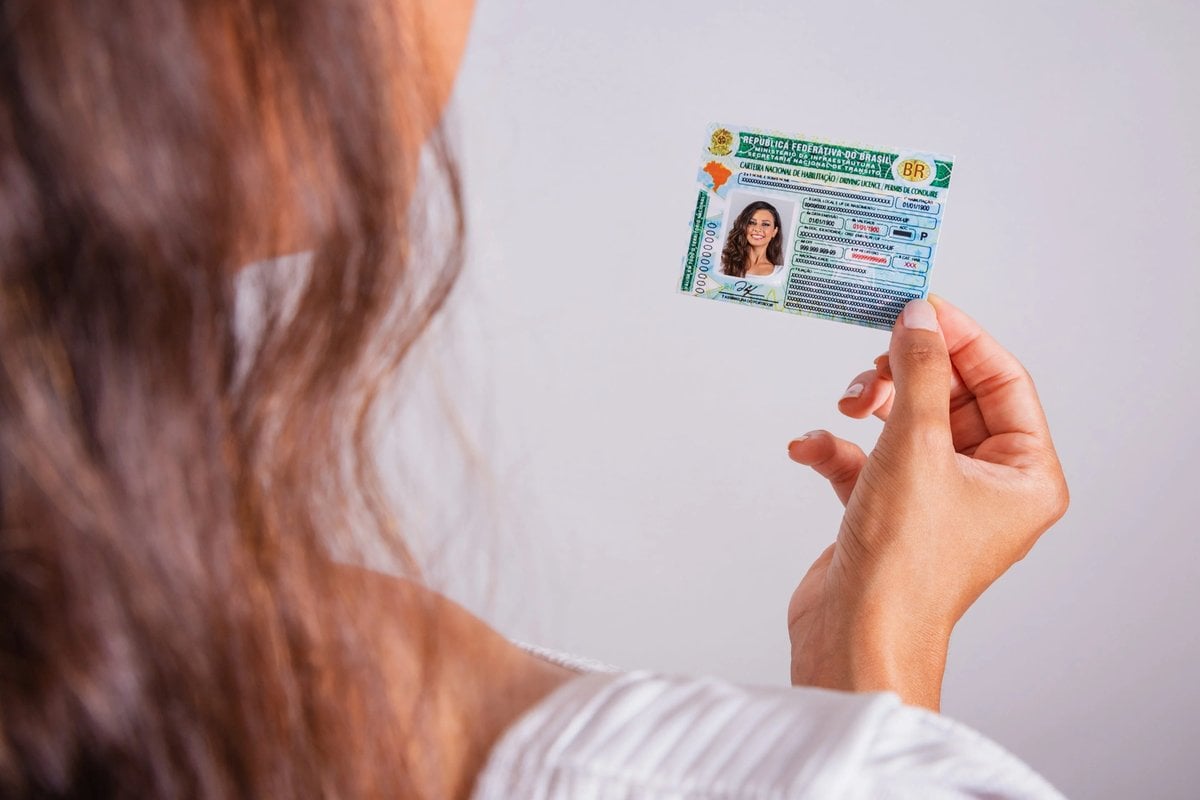 Mulher segurando sua Carteira Nacional de Habilitação       