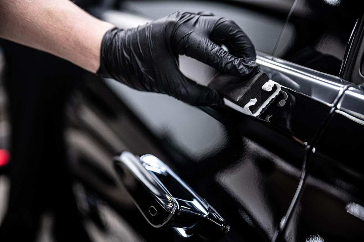 Profissional fazendo a aplicação de um produto na pintura do carro   