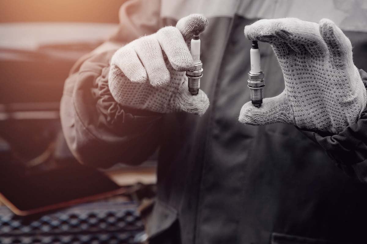 Mecânico segurando duas velas de ignição nas mãos      