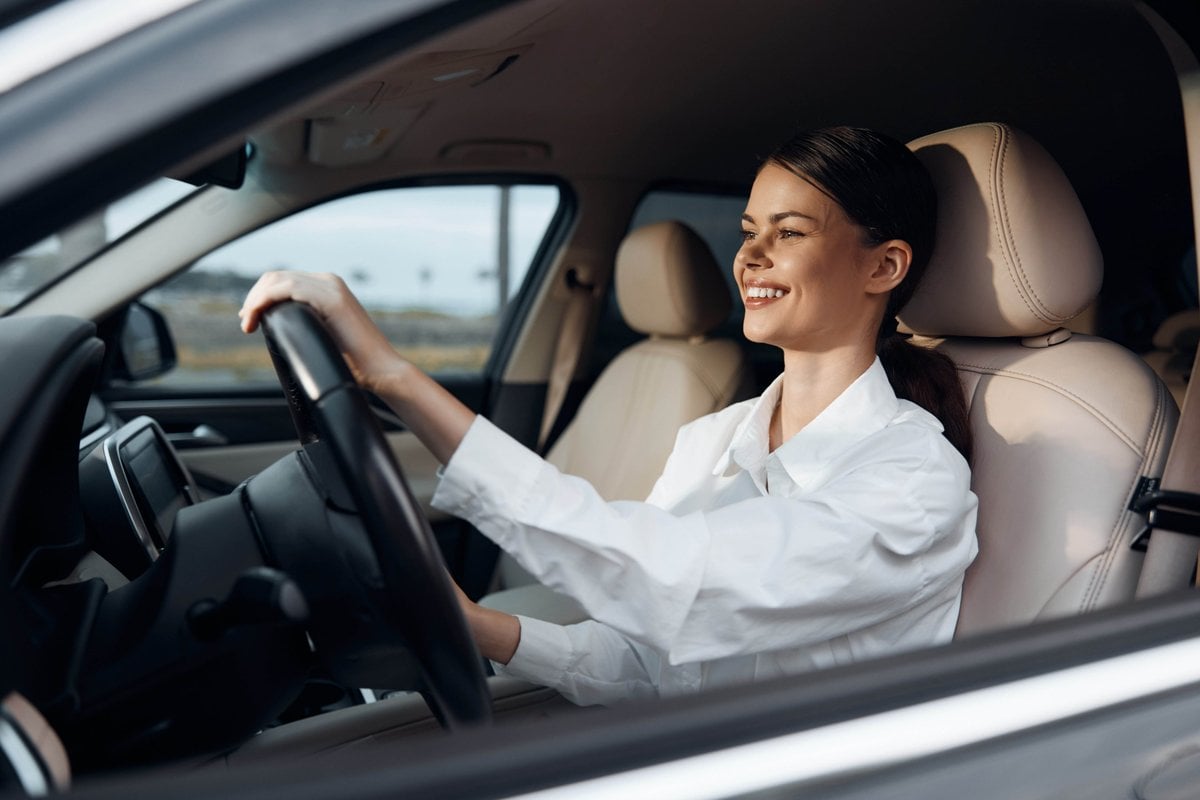 Motorista dirigindo seu carro e sorrindo        