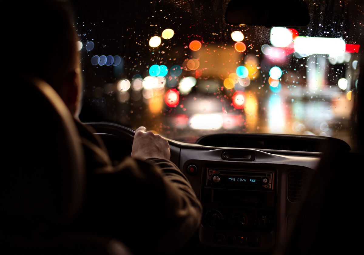 Motorista dirigindo seu carro a noite enquanto chove      