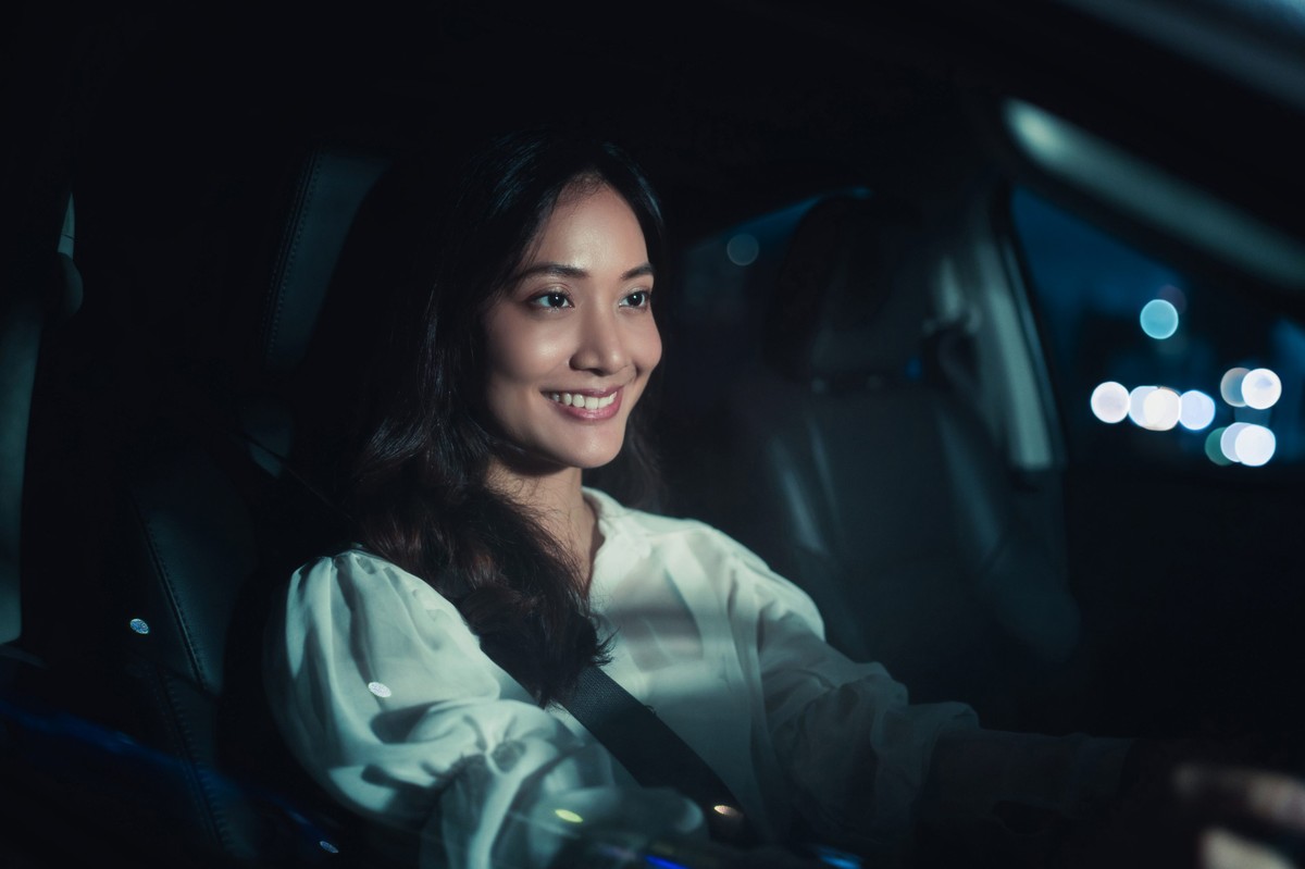 Motorista dirigindo seu carro a noite e sorrindo      