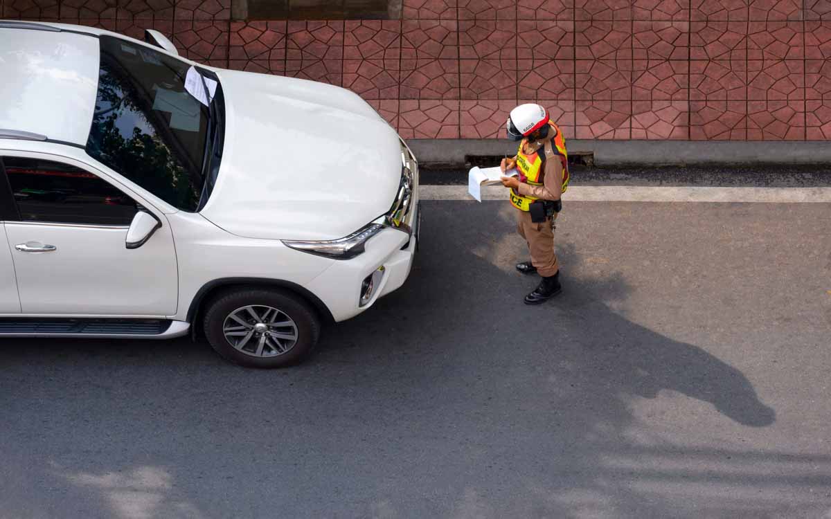 Oficial da CET aplicando uma multa em um veículo     