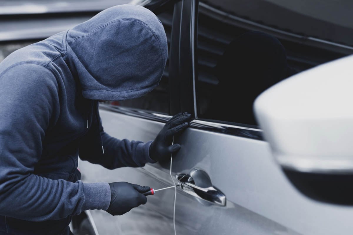 Ladrão tentando arrombar a porta do carro       