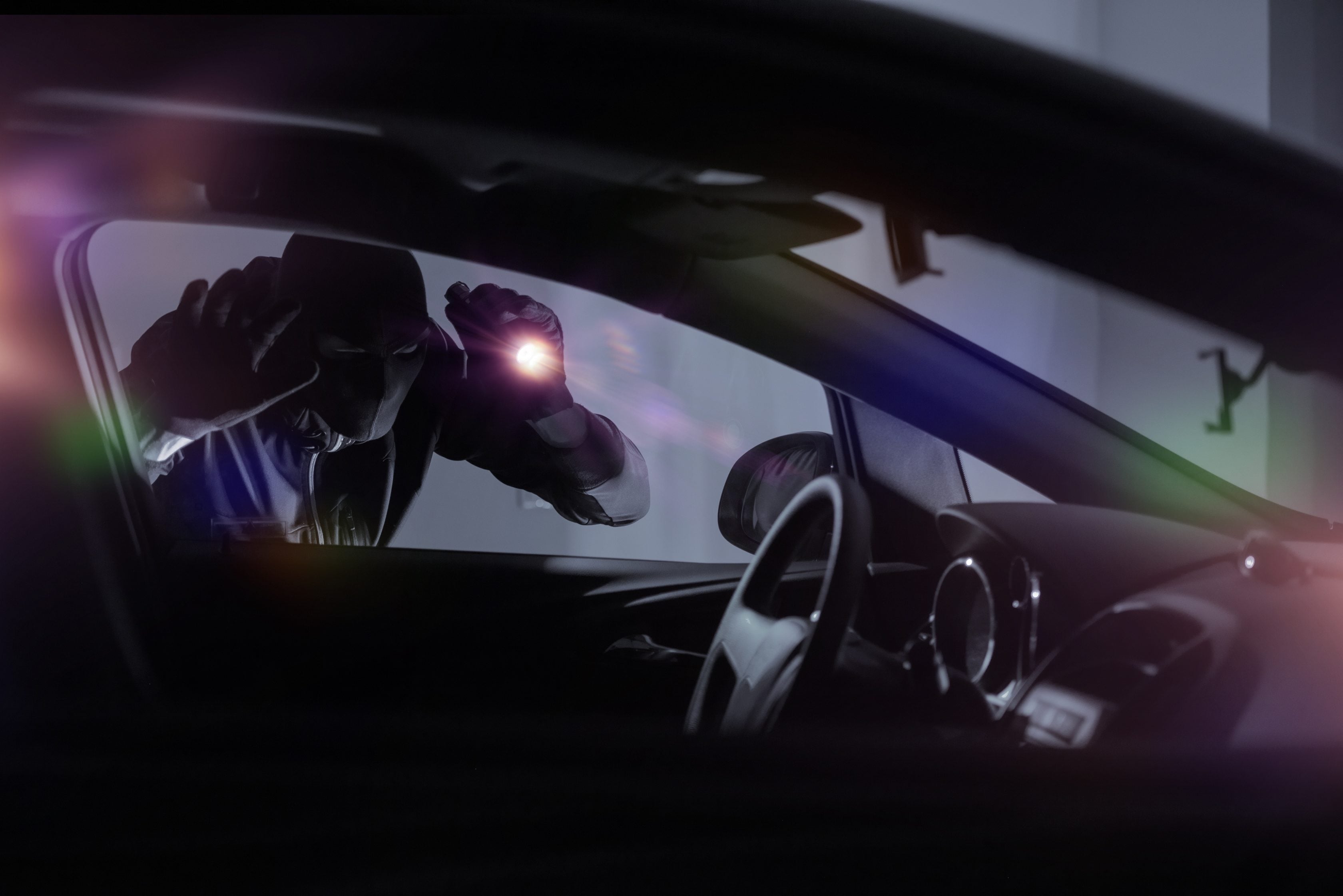 Ladrão tentando ver o que tem dentro de um carro    