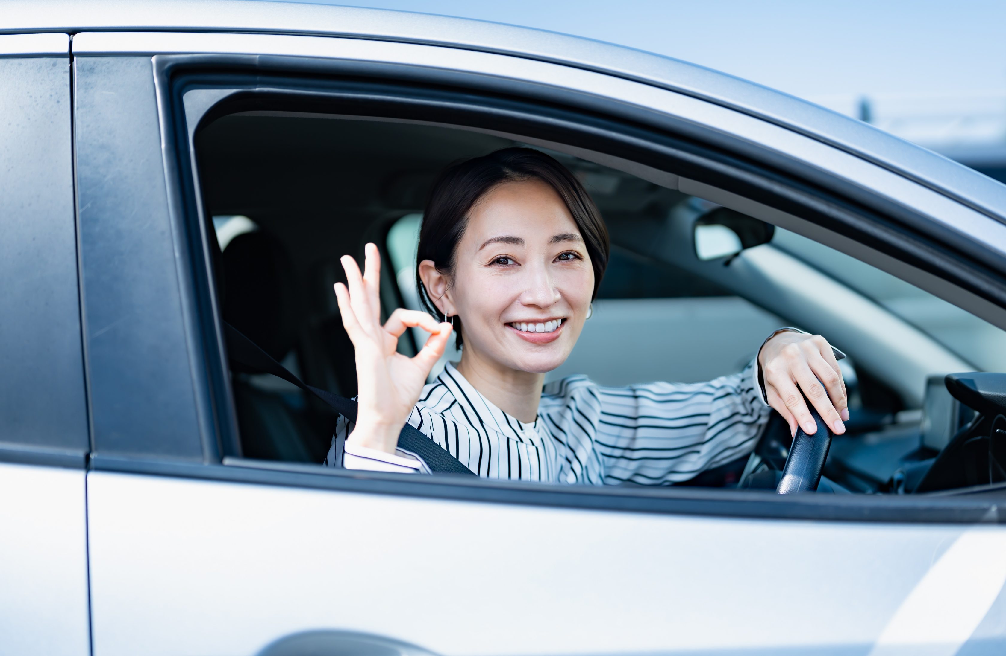 Mulher dentro do seu carro sorrindo        