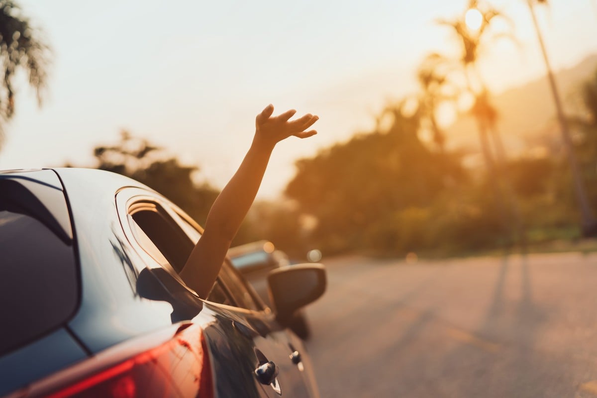 Pessoa colocando o braço para fora da janela do carro    