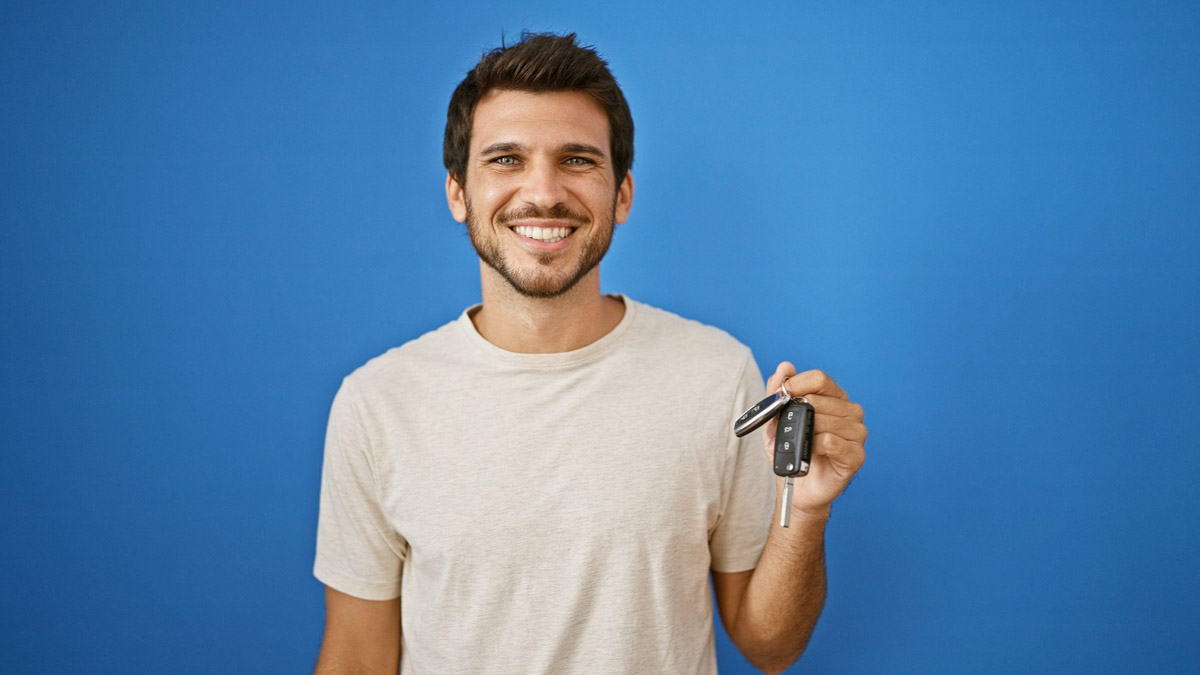 Homem segurando a chave de um carro sorrindo      