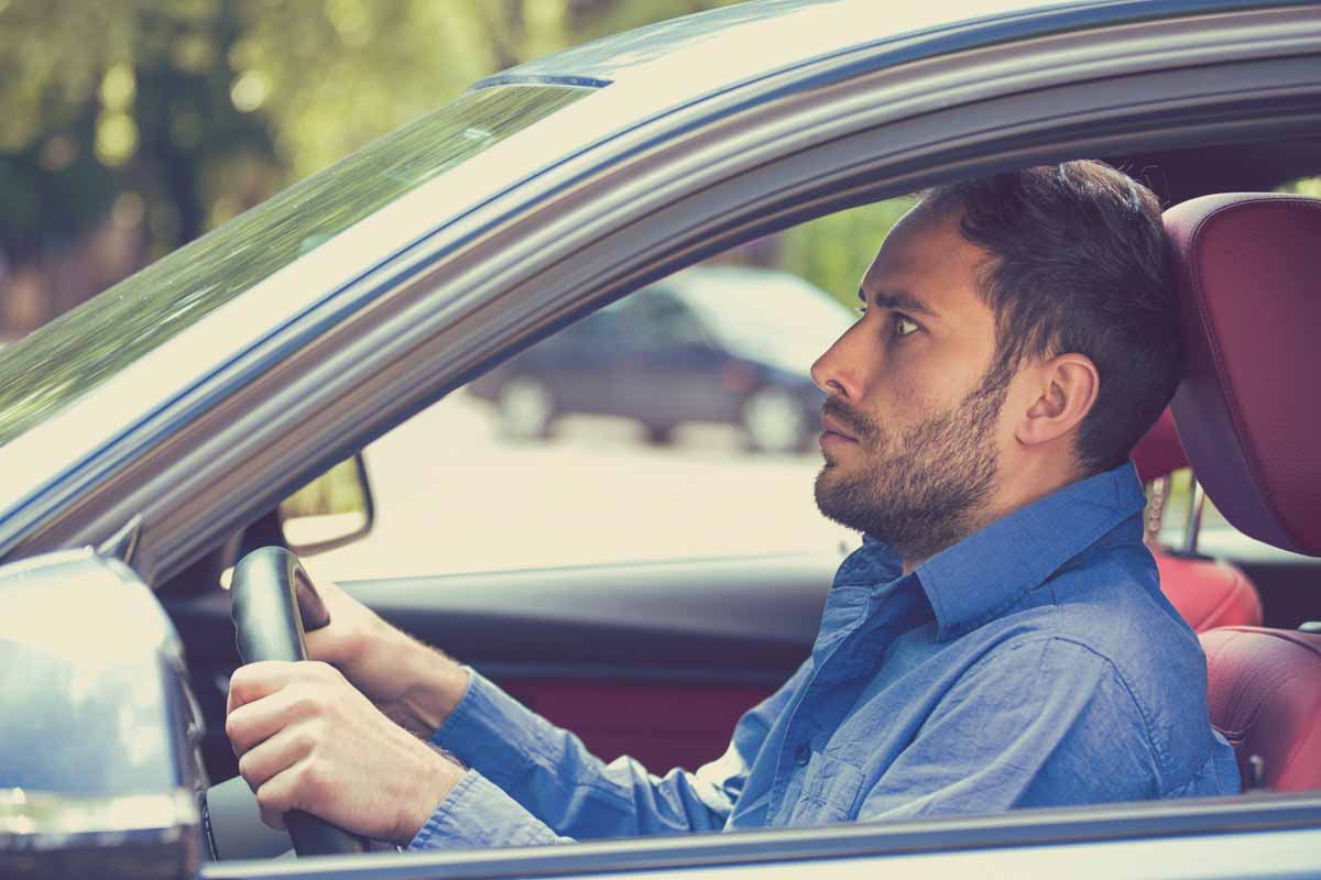 Homem com a feição assustada enquanto dirige um veículo     