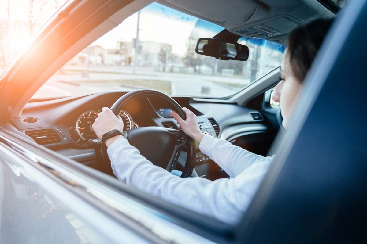mulher dentro de um carro com as mãos no volante