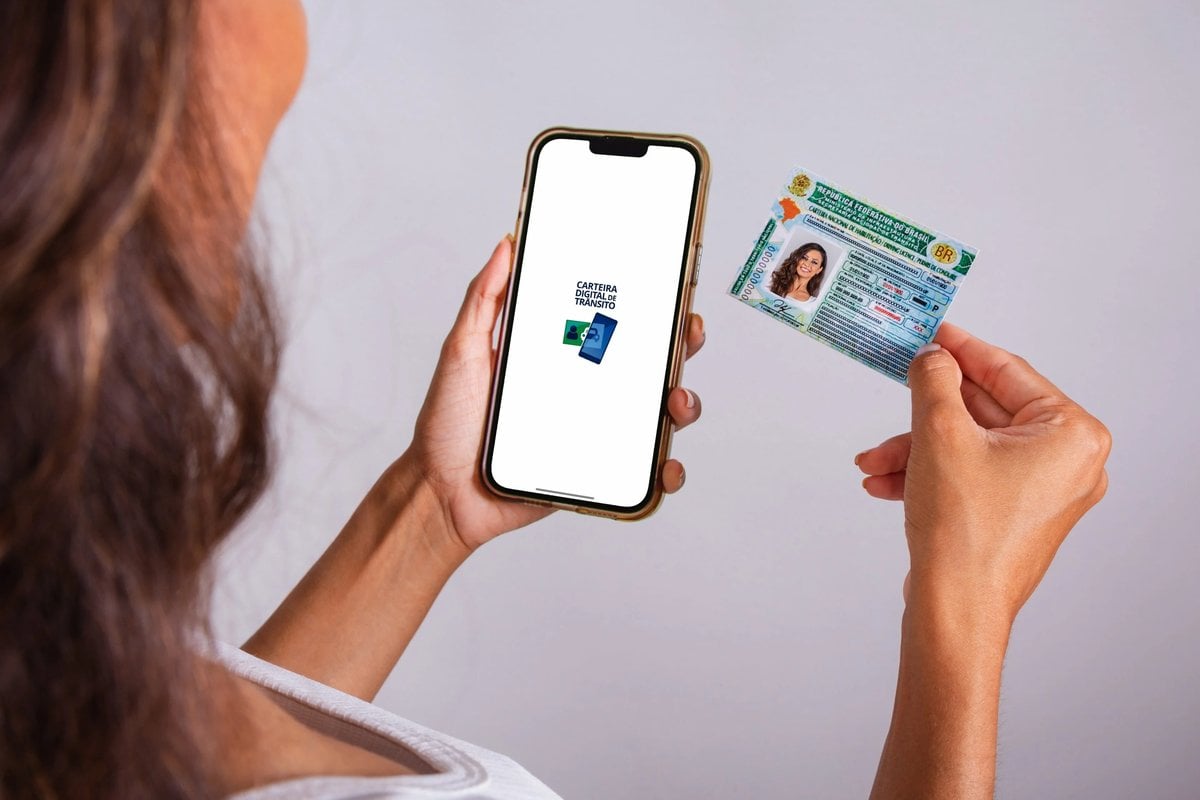 Mulher utilizando o celular e segurando sua CNH      