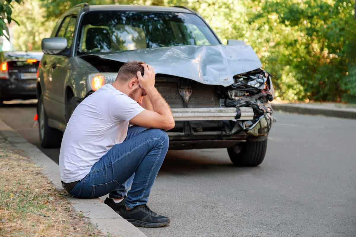 Homem aflito com as mãos na cabeça após colidir seu veículo   