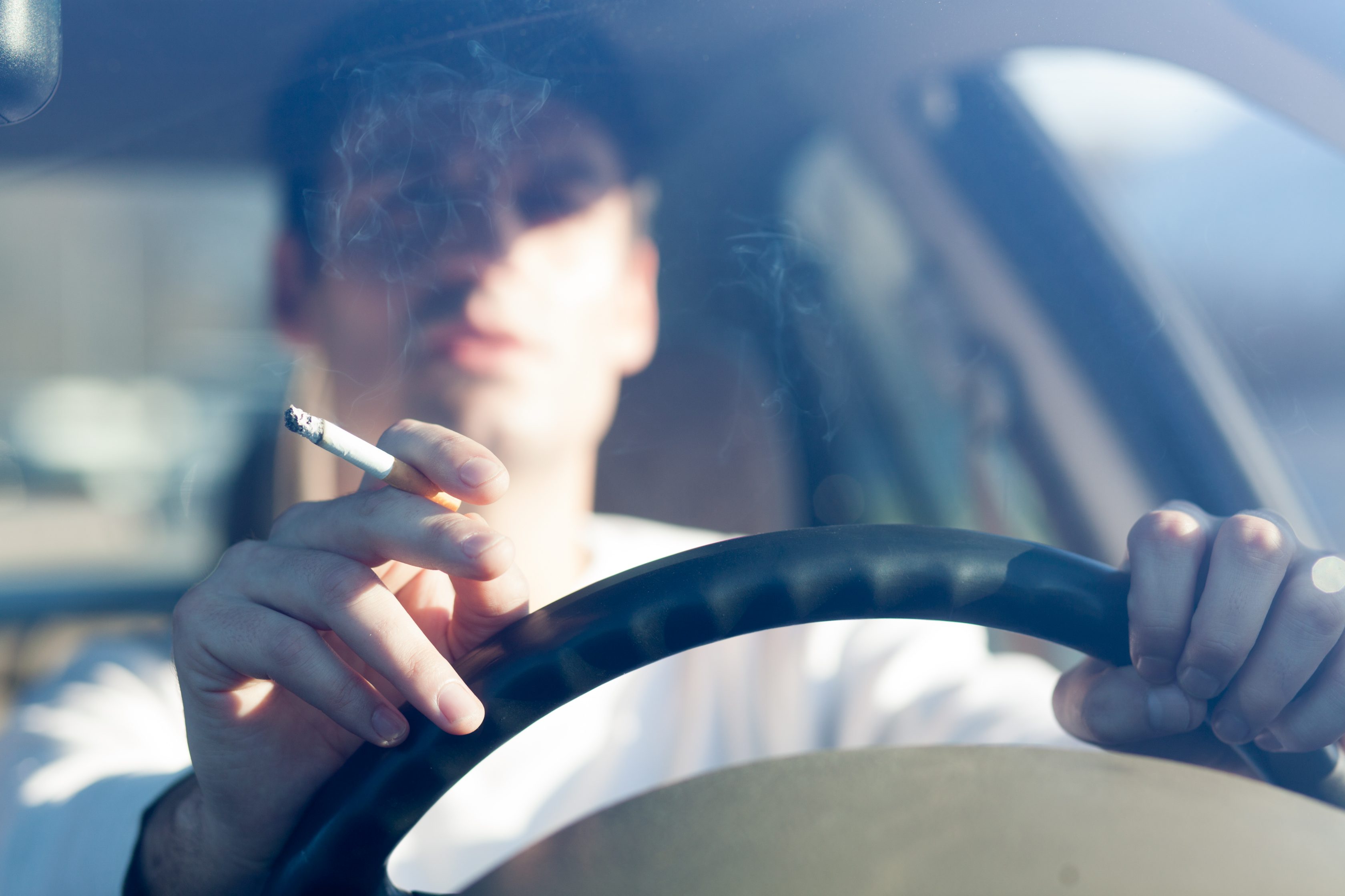 Homem dirigindo seu carro e fumando        
