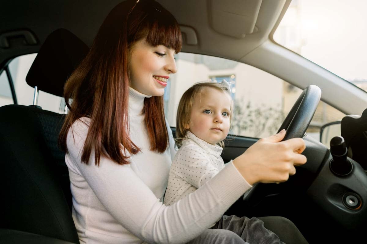 Mãe dirigindo seu carro com seu filho no colo     