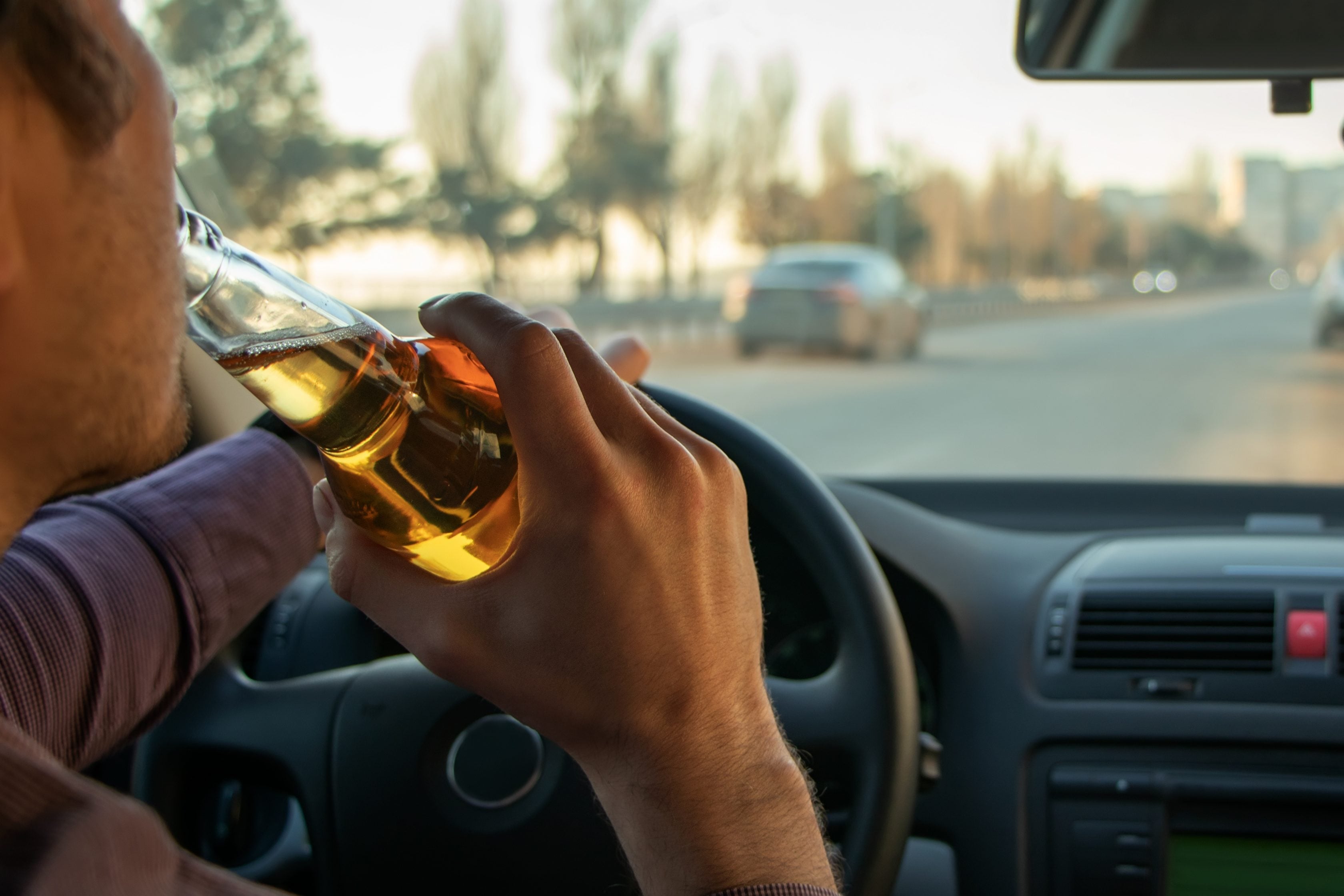 Motorista dirigindo seu carro e bebendo cerveja       