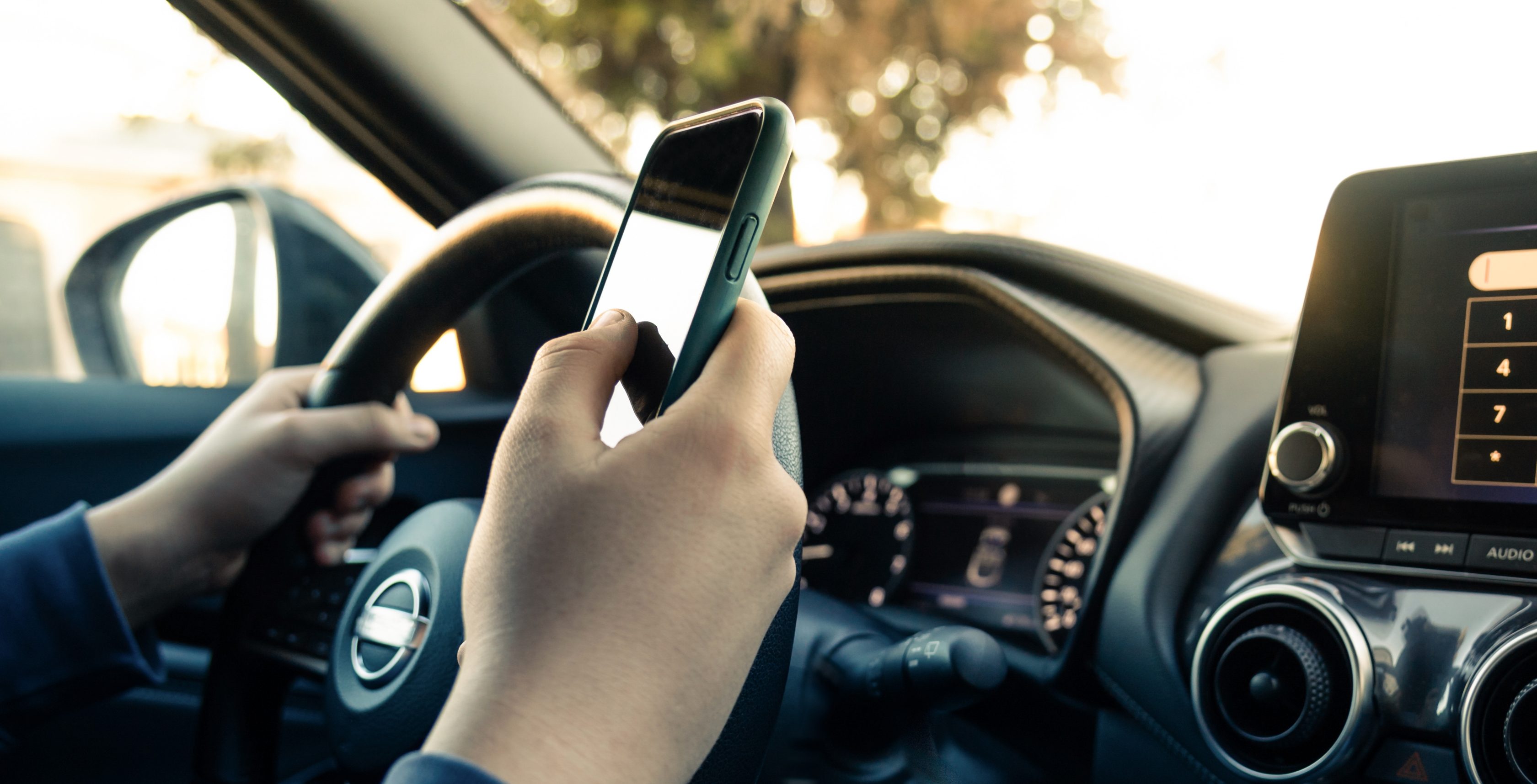 Homem dirigindo seu carro e utilizando o celular      