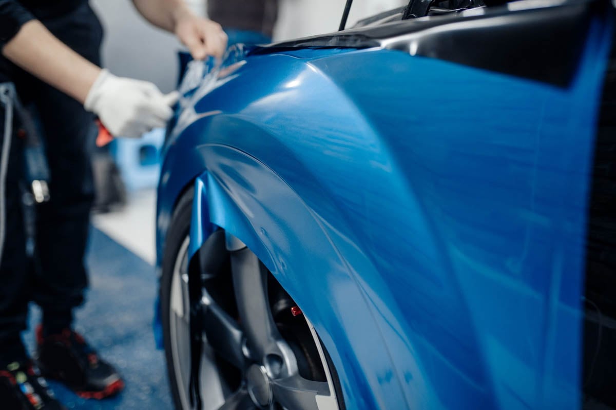 Profissionais realizando um envelopamento de um carro       