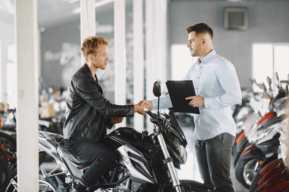 Homem apertando a mão do vendedor ao comprar sua novo moto.