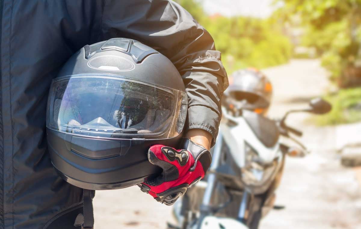 Motociclista com capacete de moto em mãos