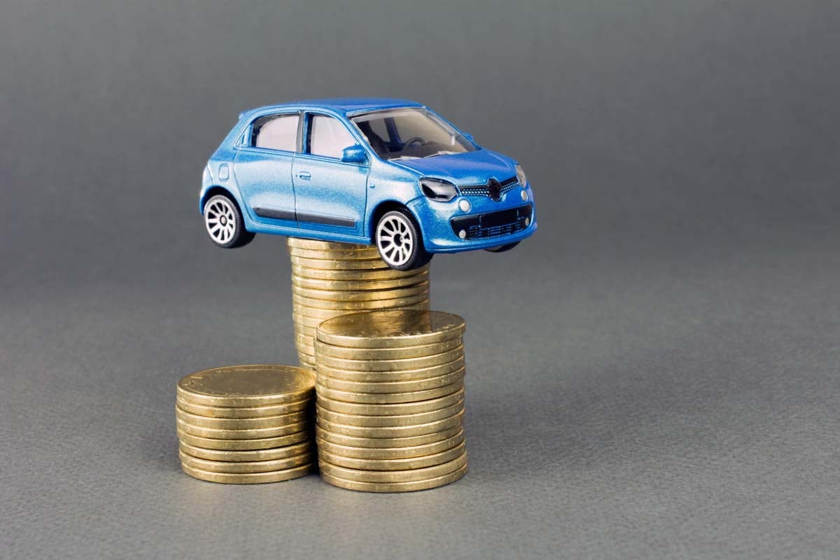 Miniatura de um carro em cima de uma pilha de moedas   