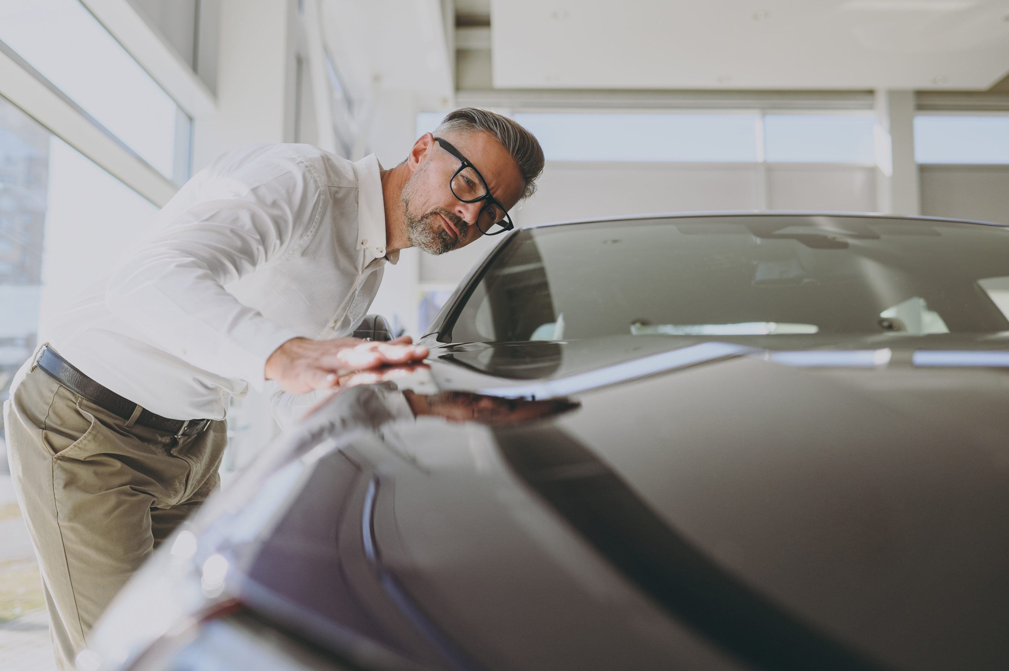 Homem conferindo o capô de um carro       