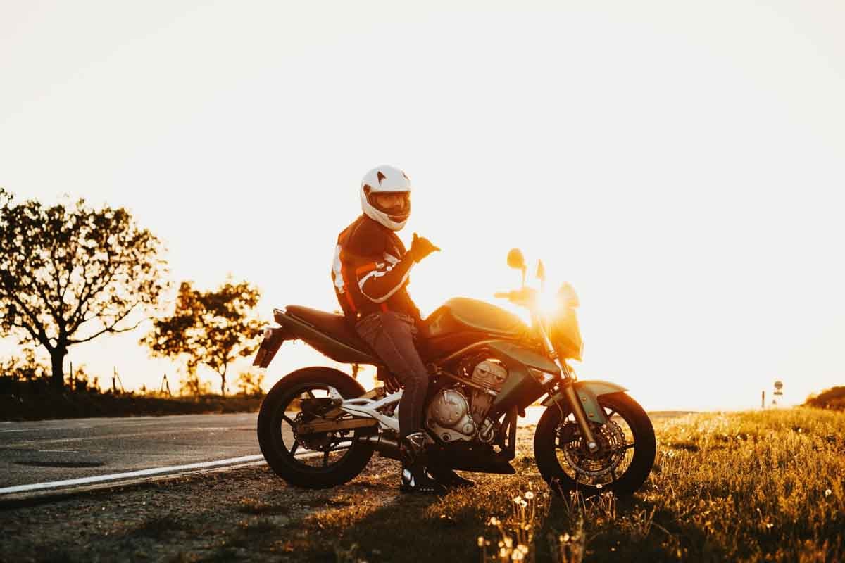 Motociclista em cima da sua moto fazendo sinal de positivo