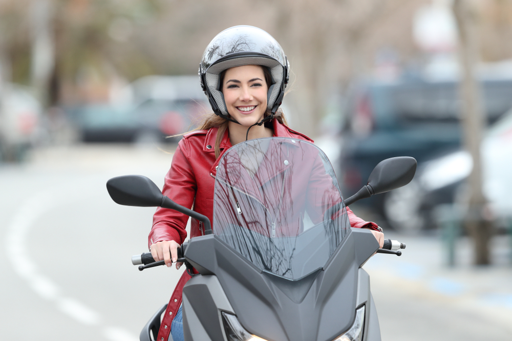 Mulher pilotando uma moto sorrindo