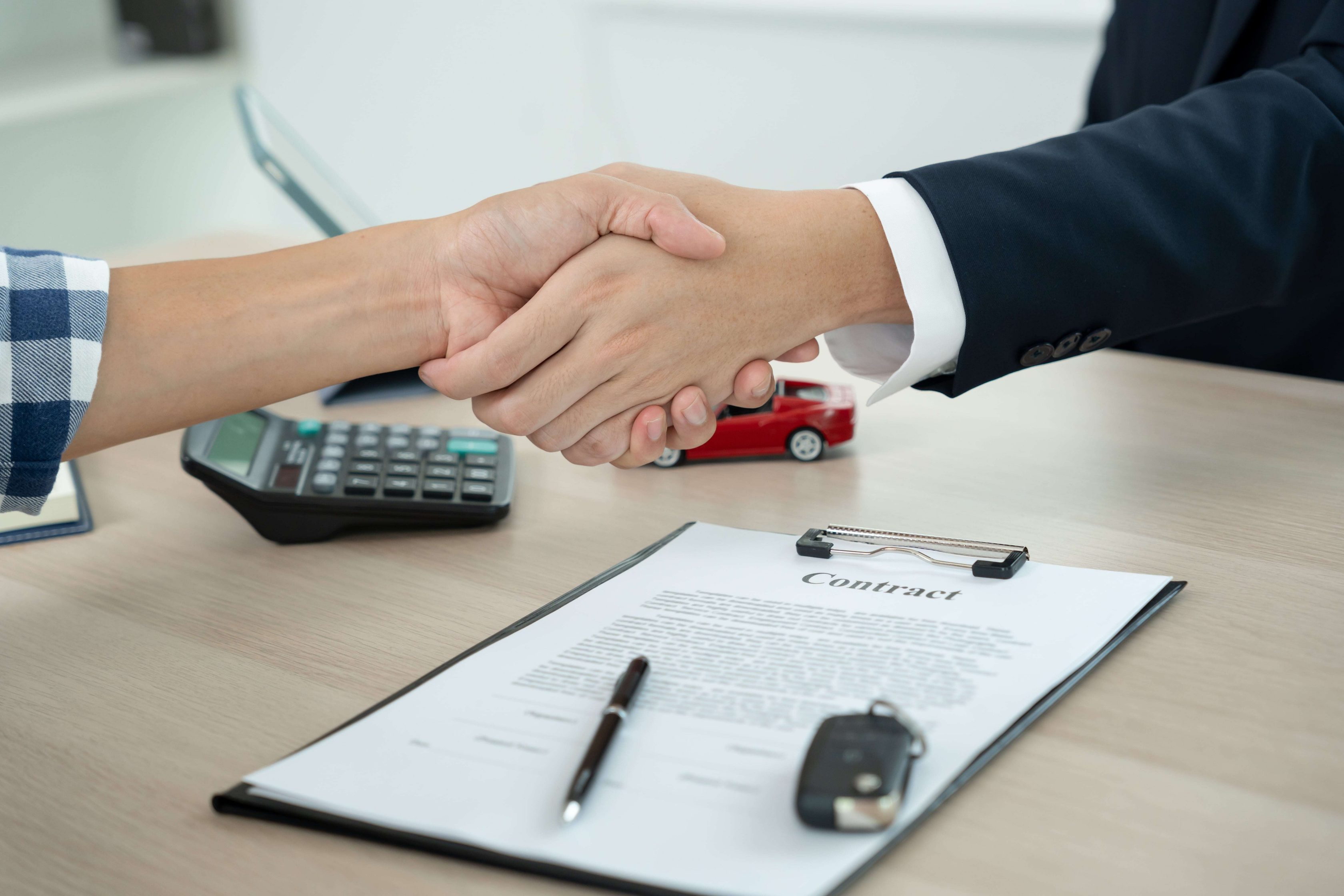 Pessoas apertando a mão após negociar um veículo