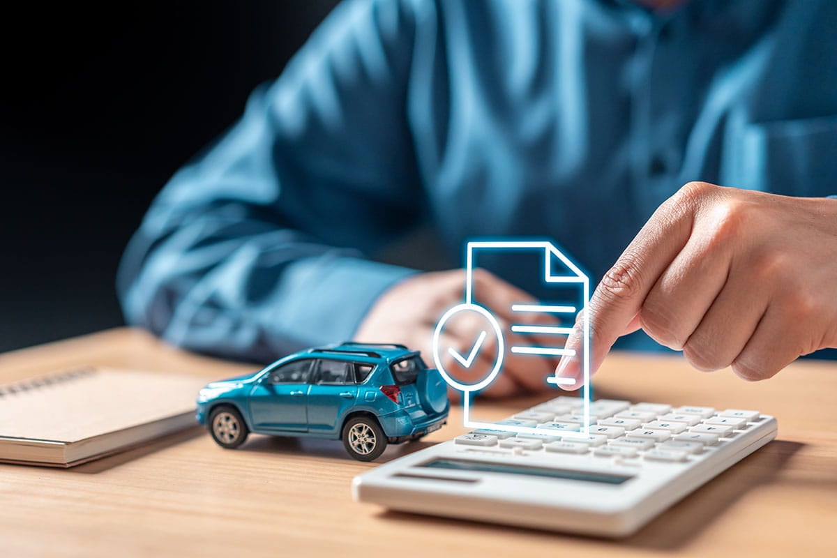 Miniatura de carro e homem com calculadora representando o seguro de carro