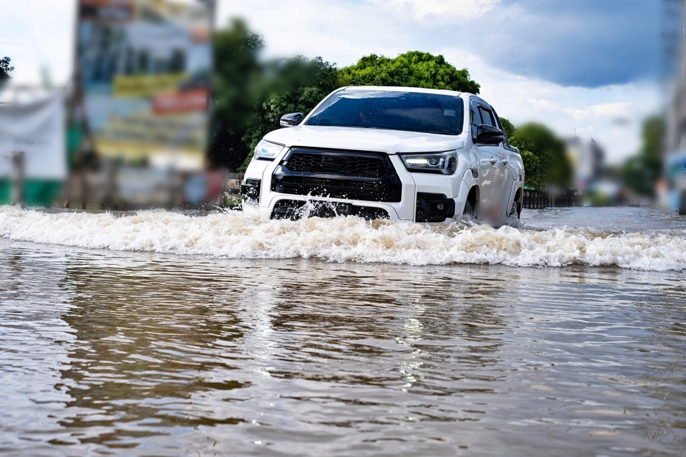 Carro branco passando por uma enchente