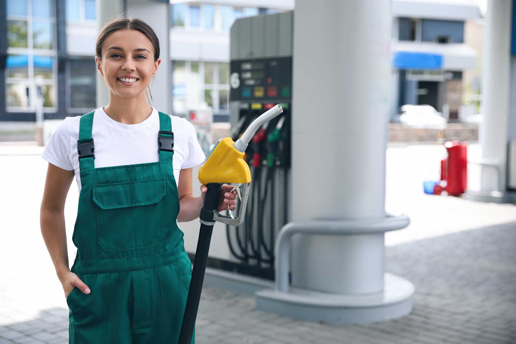 Mulher frentista sorrindo e segurando a mangueira de combustível