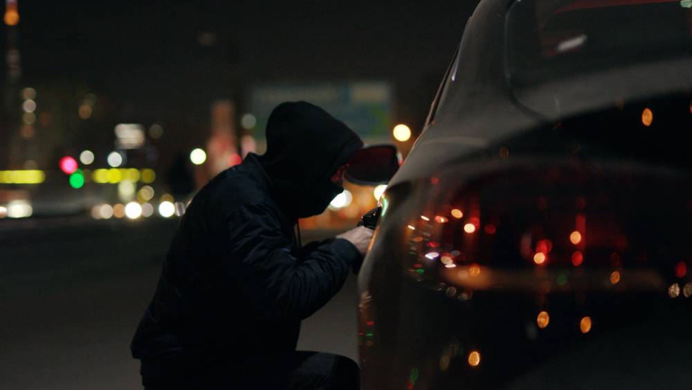 Bandido furtando um carro estacionado na rua