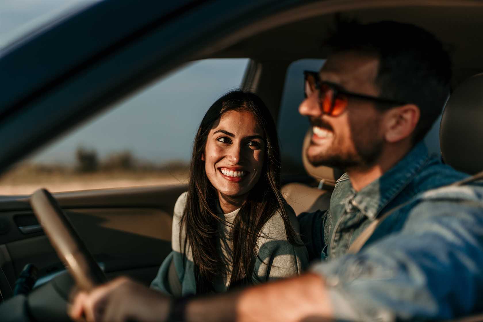 Casal sorrindo e viajando de carro