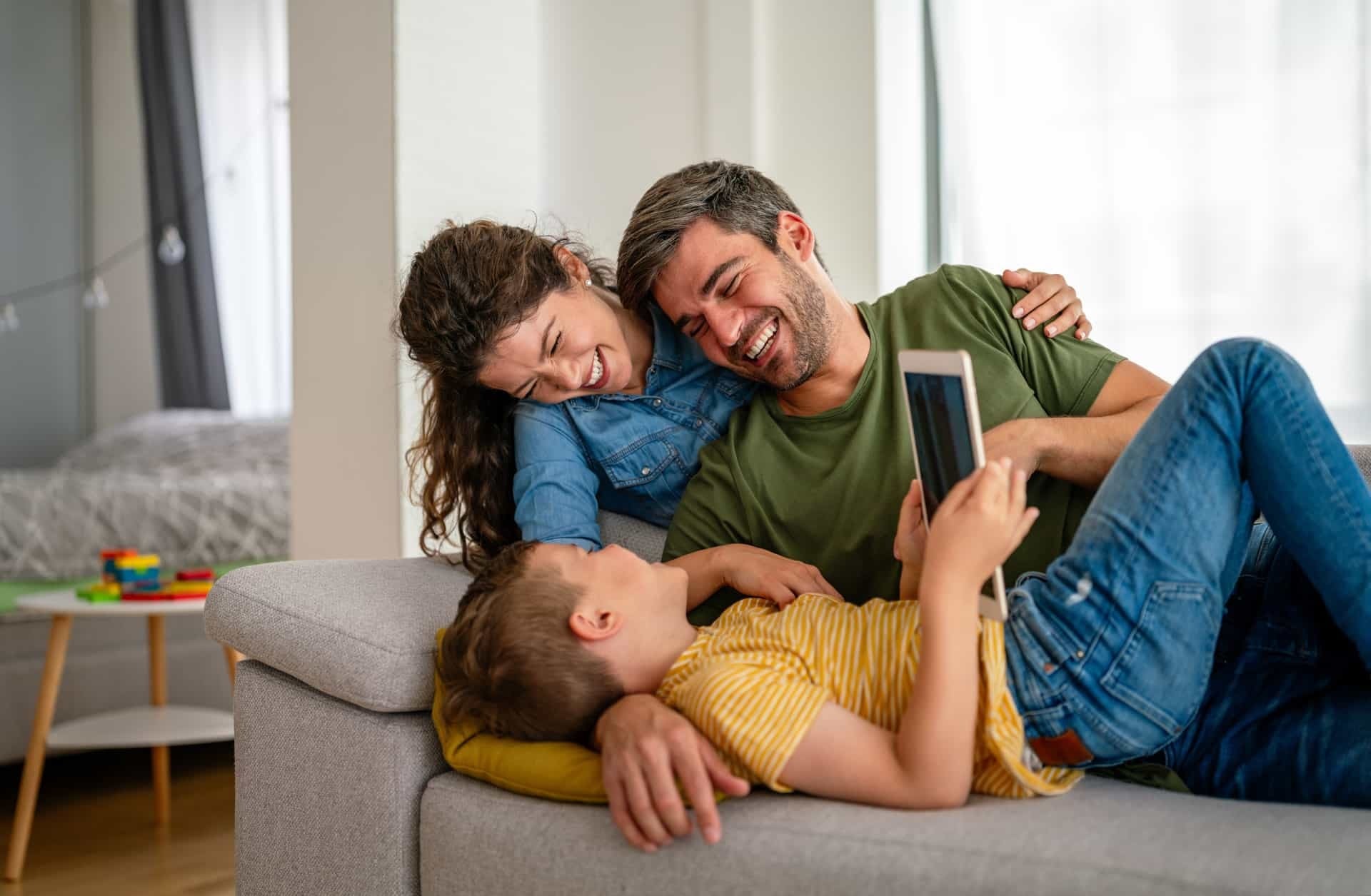 Família feliz rindo e brincando no sofá