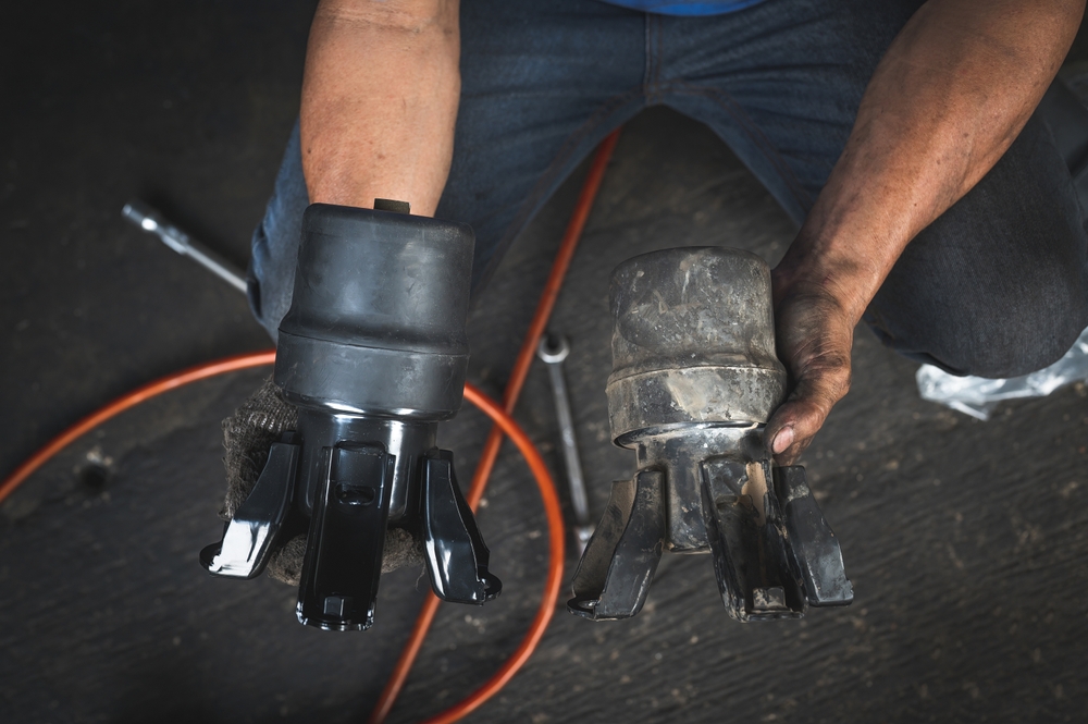 Mecânico mostrando um coxim do motor novo e um coxim do motor com desgaste