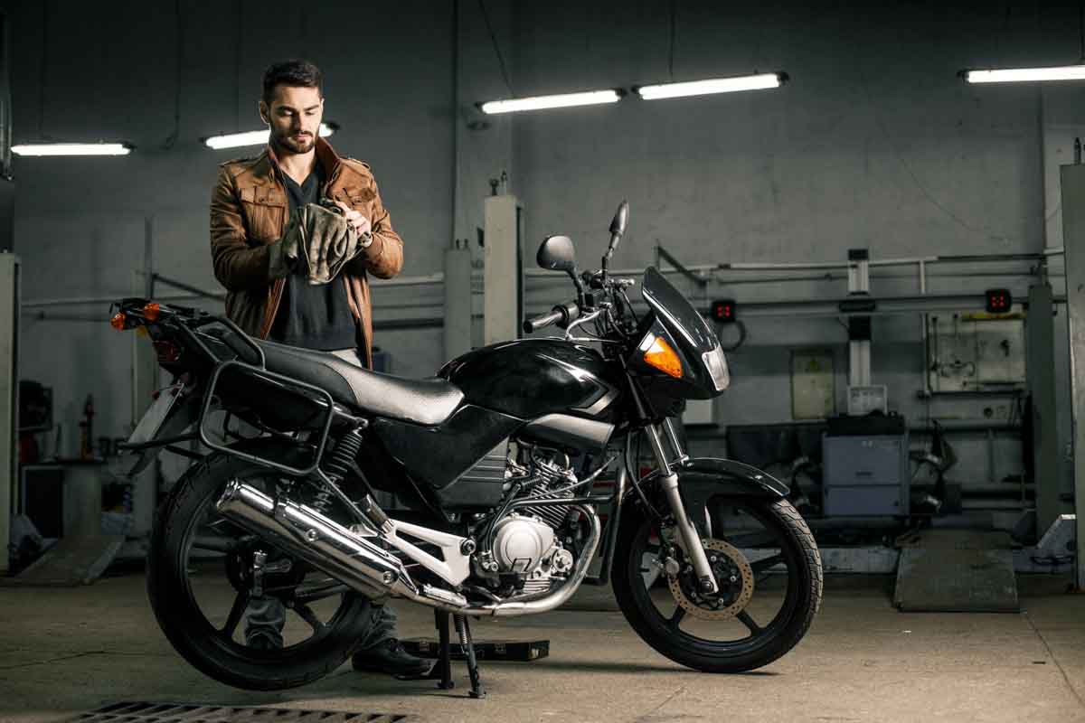 Homem e sua motocicleta na oficina mecânica