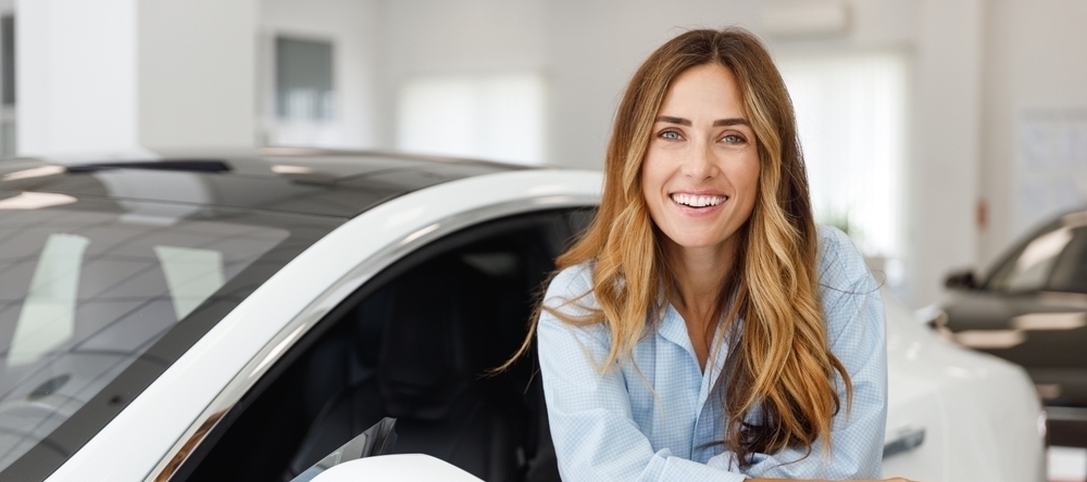 Mulher loira sorrindo de dentro do carro