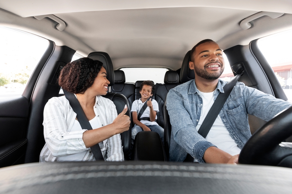 Família sorrindo no carro com o cinto de segurança