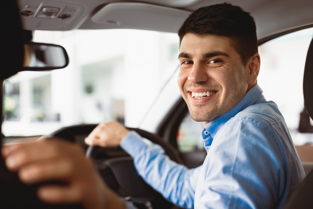 Homem sorrindo dentro do carro