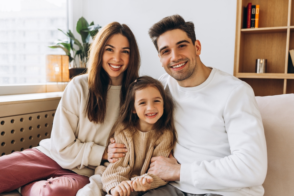 Família feliz sorrindo no sofá