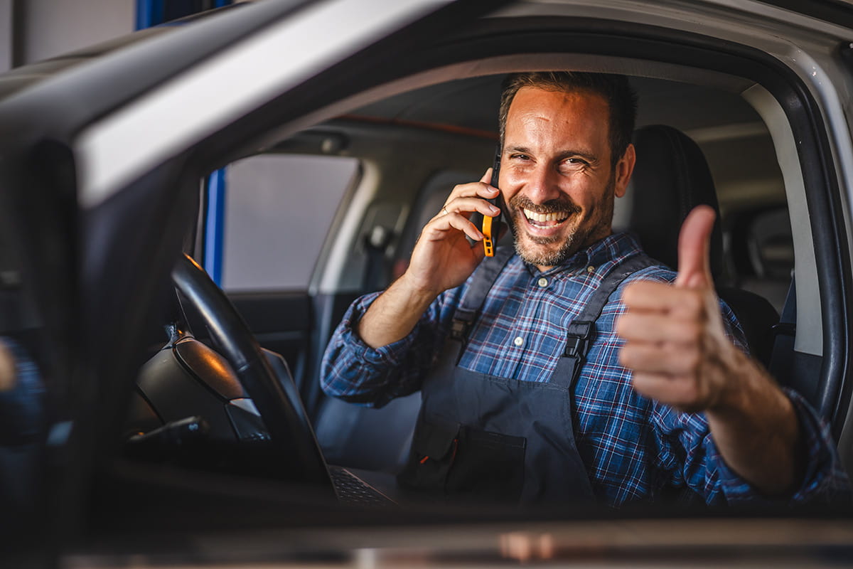 Mecânico dentro do carro sorrindo