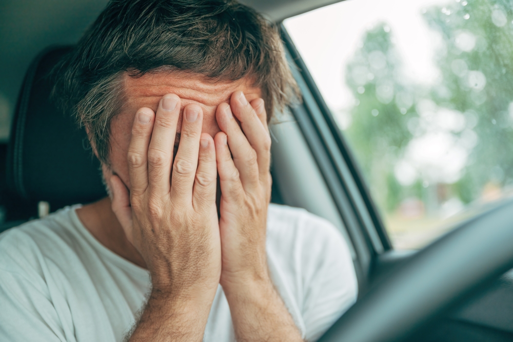 Motorista triste com as mãos no rosto