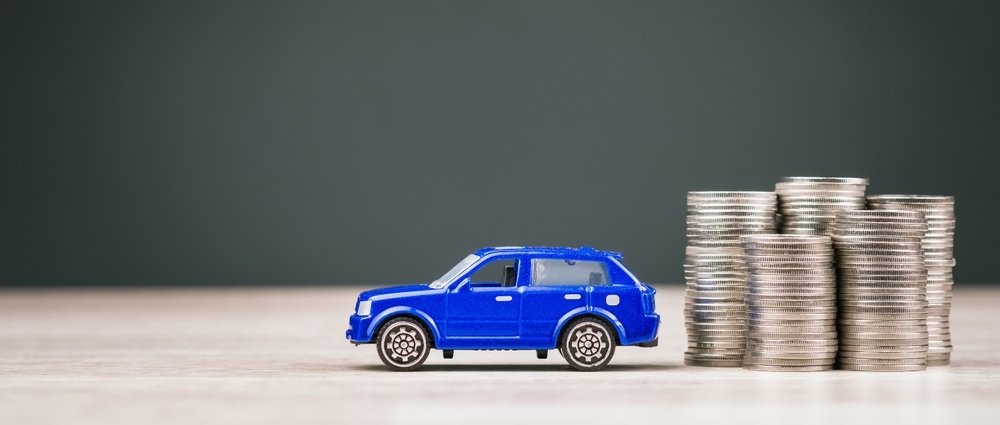 Miniatura de carro ao lado de moedas simbolizando a restituição de IPVA