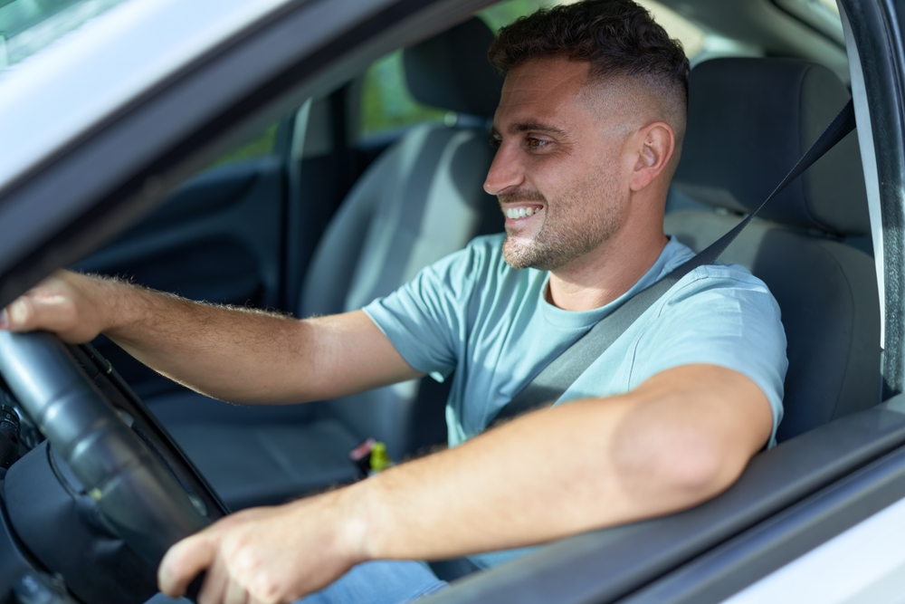 Homem jovem sorrindo confiante ao dirigir