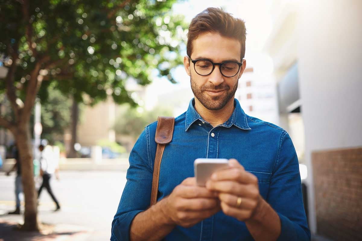 Homem feliz e sorrindo olhando para o celular